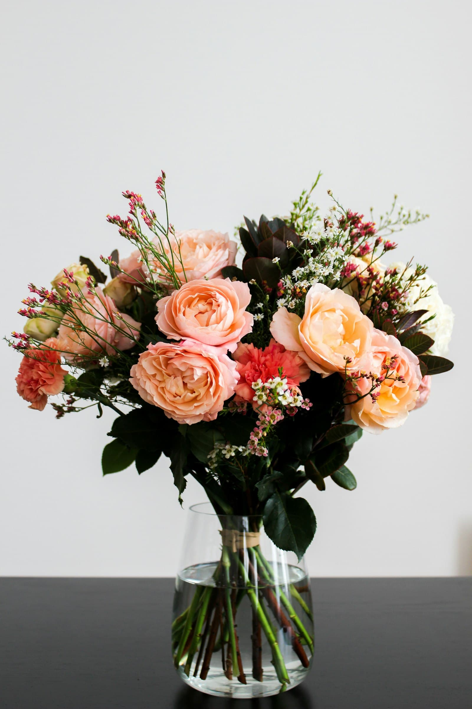 Coral and peach roses with spray roses in a glass vase