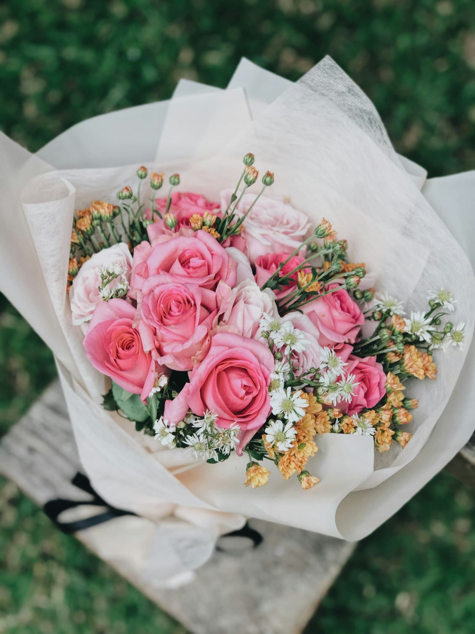 Hand-wrapped bouquet of pink and white roses with waxflower